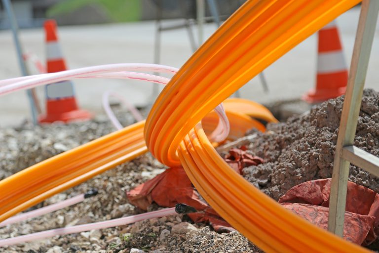 Orange pipes for fiber optics in a large city road construction to connect high speed internet